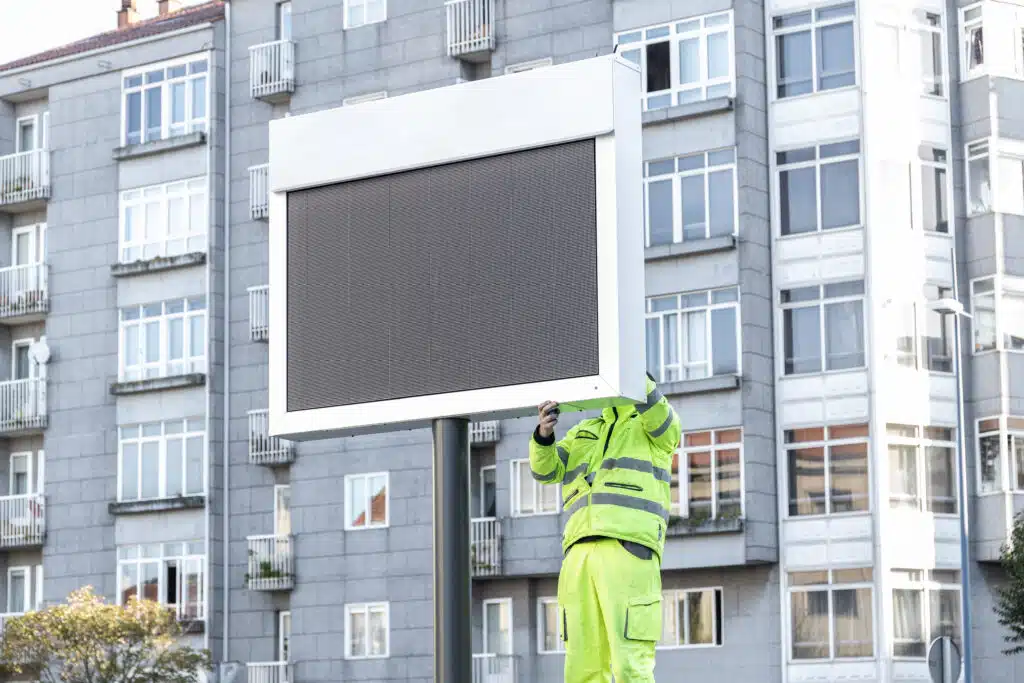 Worker installing a new electronic sign on city street. Mock up