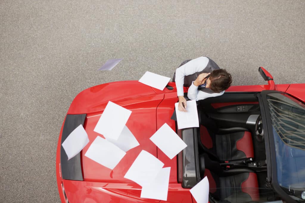 Blowing papers from man's electric car