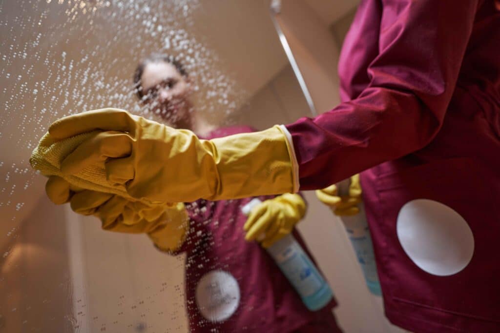 janitor-in-rubber-gloves-wiping-down-mirror-2023-11-27-05-02-13-utc_11zon