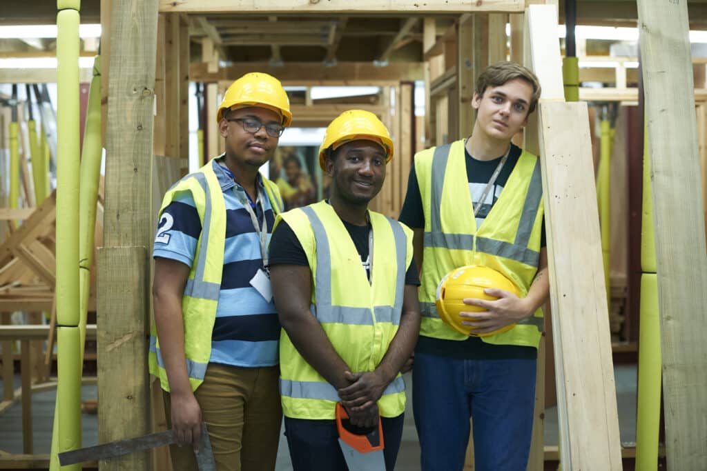 Three male higher education carpentry students in college workshop, portrait